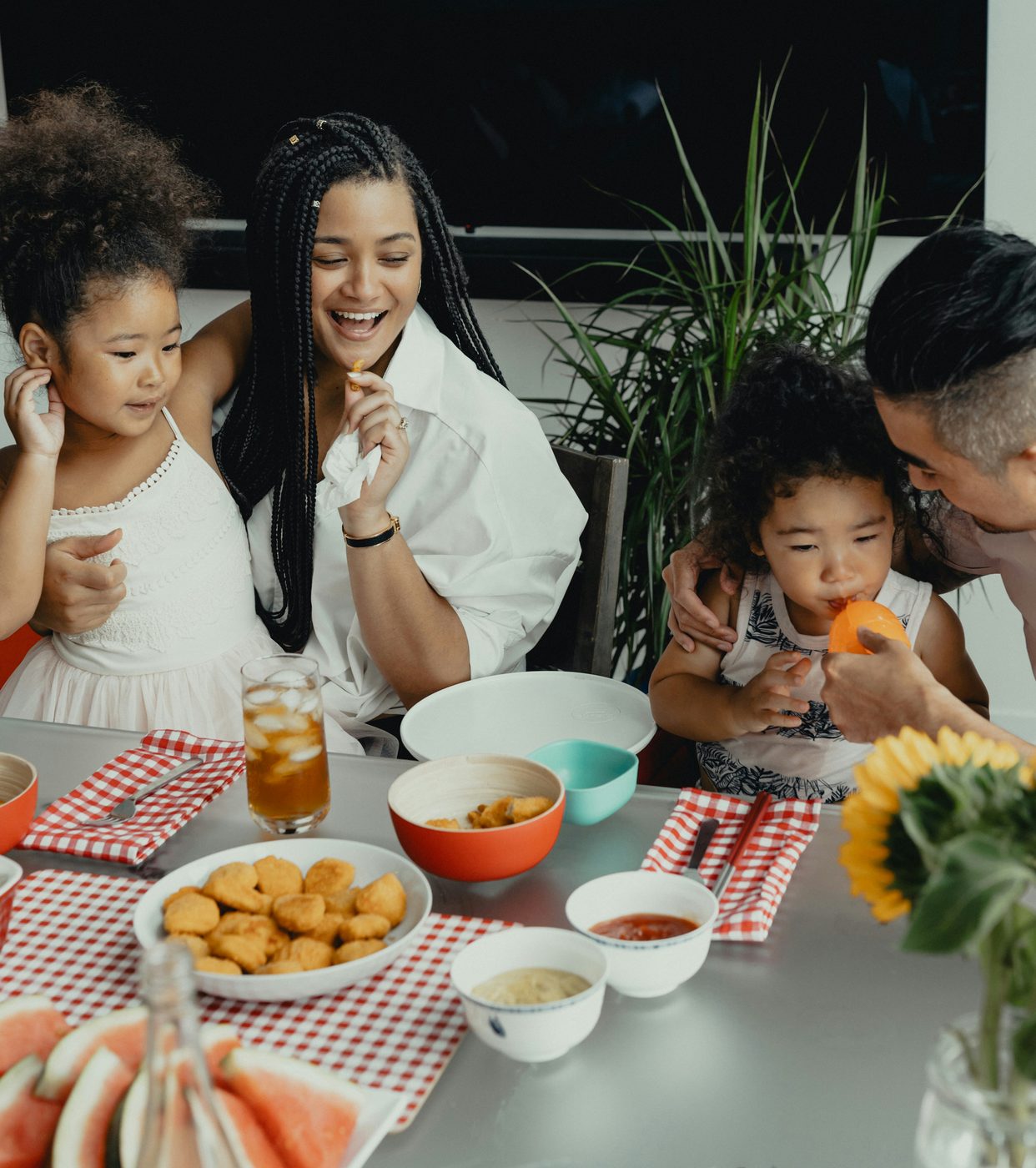A family of four sharing a meal together — parents and two young children at the kitchen table